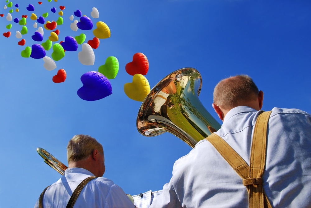 Blasmusiker spielen Musik und Luftballonherzen steigen zum Himmel.
